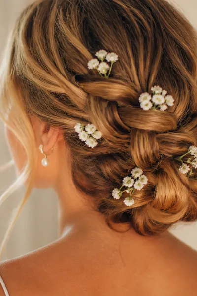 braided low bun prom updo with baby's breath flowers — romantic hairstyle