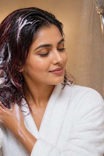Woman caring for color-treated hair in shower with color-safe products — maintenance routine