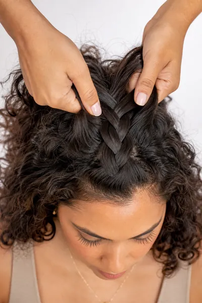 Step-by-step instructional image showing hands performing Dutch braid technique with strands crossing under the middle strand