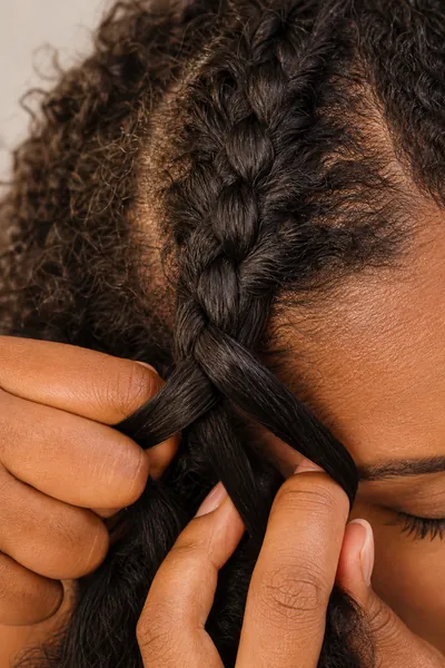 Close-up macro photograph showing underhand strand crossing technique in a Dutch braid with detailed texture