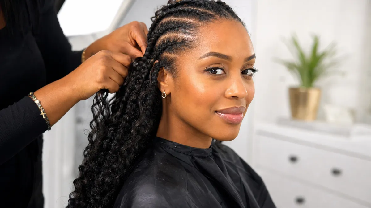 20 Goddess Braids That Make a Statement 2 woman getting goddess braids installed at a salon showing visible cornrow base during the braiding process