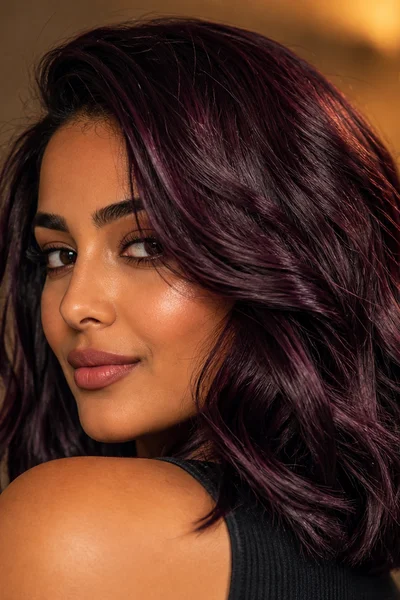Deep plum burgundy jewel-tone hair on wavy hair — sophisticated cool-undertone fall color