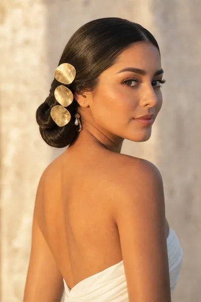 Statement-pin sculpted chignon — elegant, formal prom updo elevated with oversized metal pins