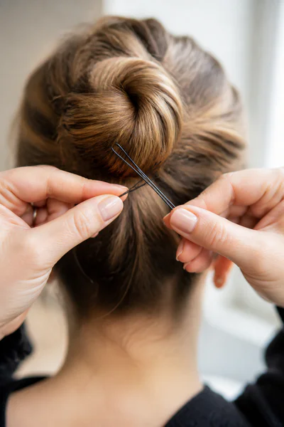 Close-up of hands crossing two bobby pins into an X pattern to secure a bun