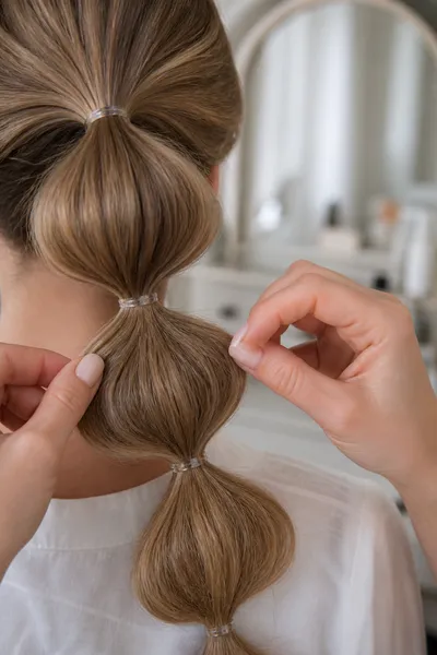 12 Bubble Bun Hairstyles That Are Trending This Year 15 Hands re-pancaking a loosened bubble section to refresh a bubble bun midday.