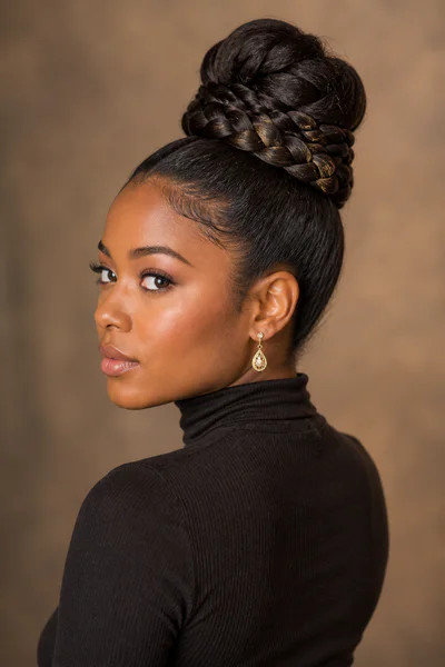 Thick braid wrapped around the base of a bun, decorative structured style