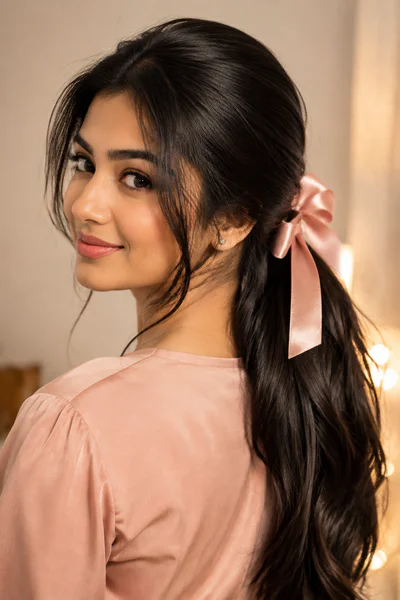 Sleek low ponytail with a satin bow, one of these homecoming hair ideas for long hair